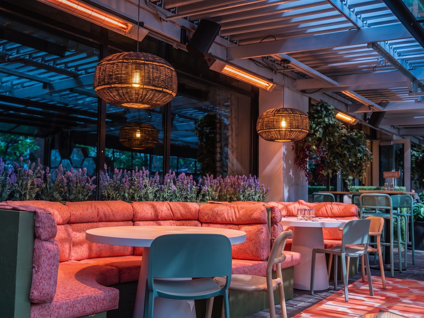 Terrasse de restaurant au crépuscule chauffée par des chauffe-terrasses radiants infrarouges installés sous la pergola SunLouvre Pergolas