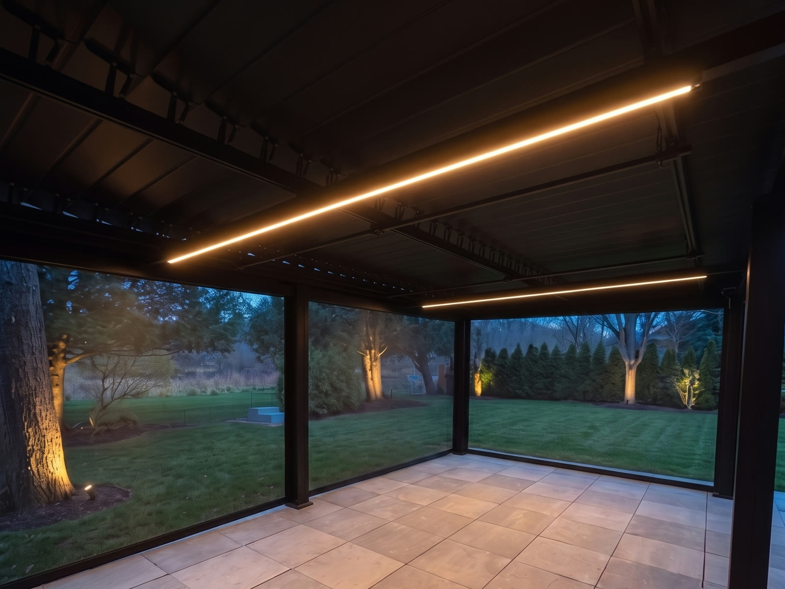 Intérieur d'une pergola en aluminium noir éclairée par des bandes DEL intégrées le soir, vue sur la cour à travers les toiles