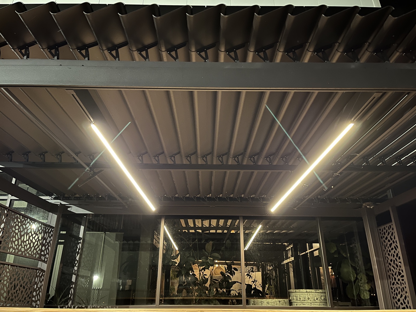 Gros plan des bandes DEL sous les poutres d'une pergola, lumière diffuse sans point lumineux