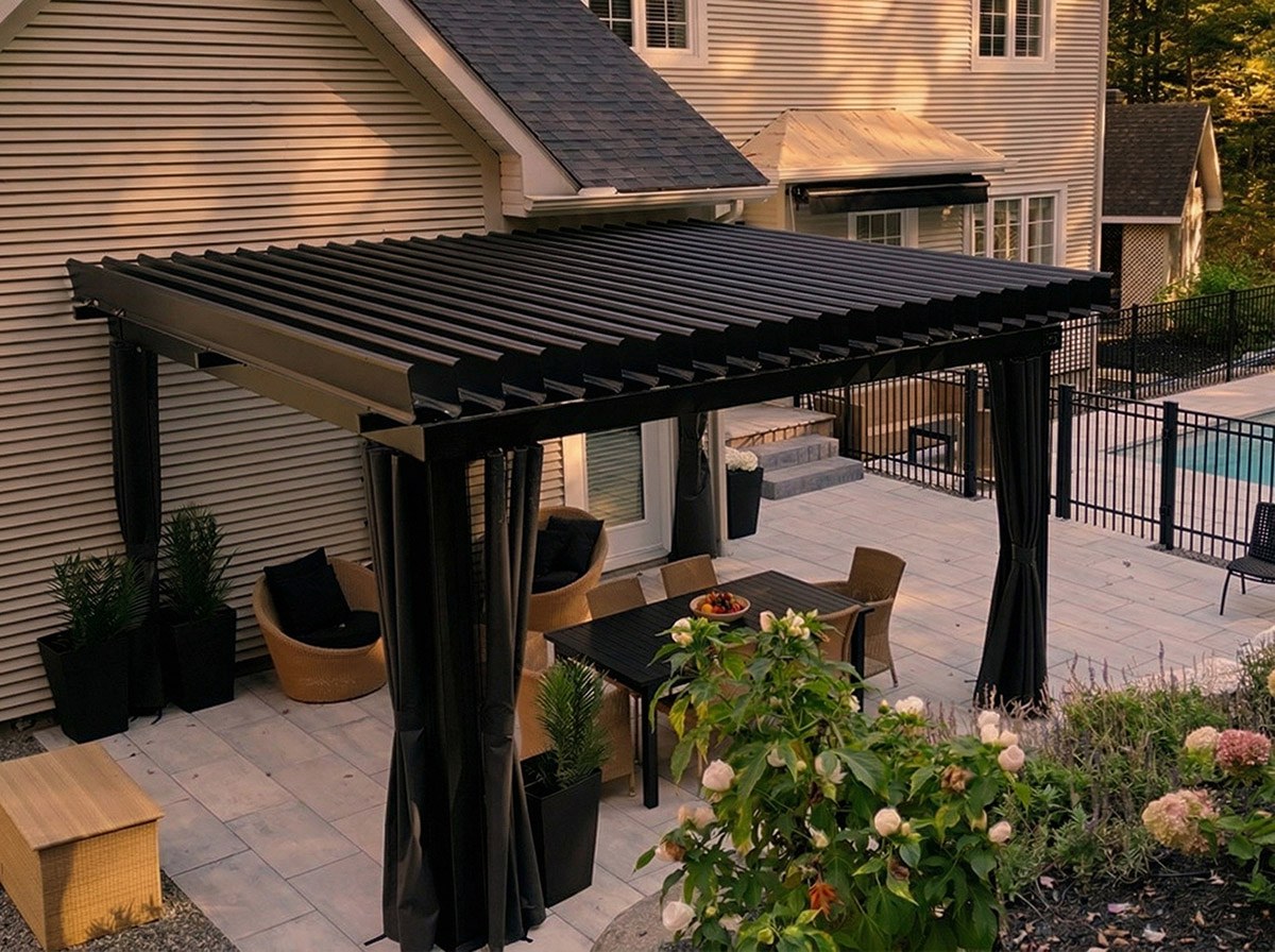 Pergola SunLouvre Pergolas noire sur patio, rideaux manuels noués à chaque poteau, mobilier de salle à manger et piscine