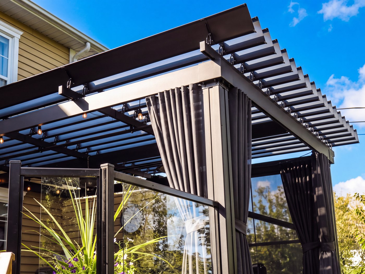 Rail de rideau manuel intégré dans la poutre d'une pergola SunLouvre Pergolas à lames orientables, rideau replié contre le poteau