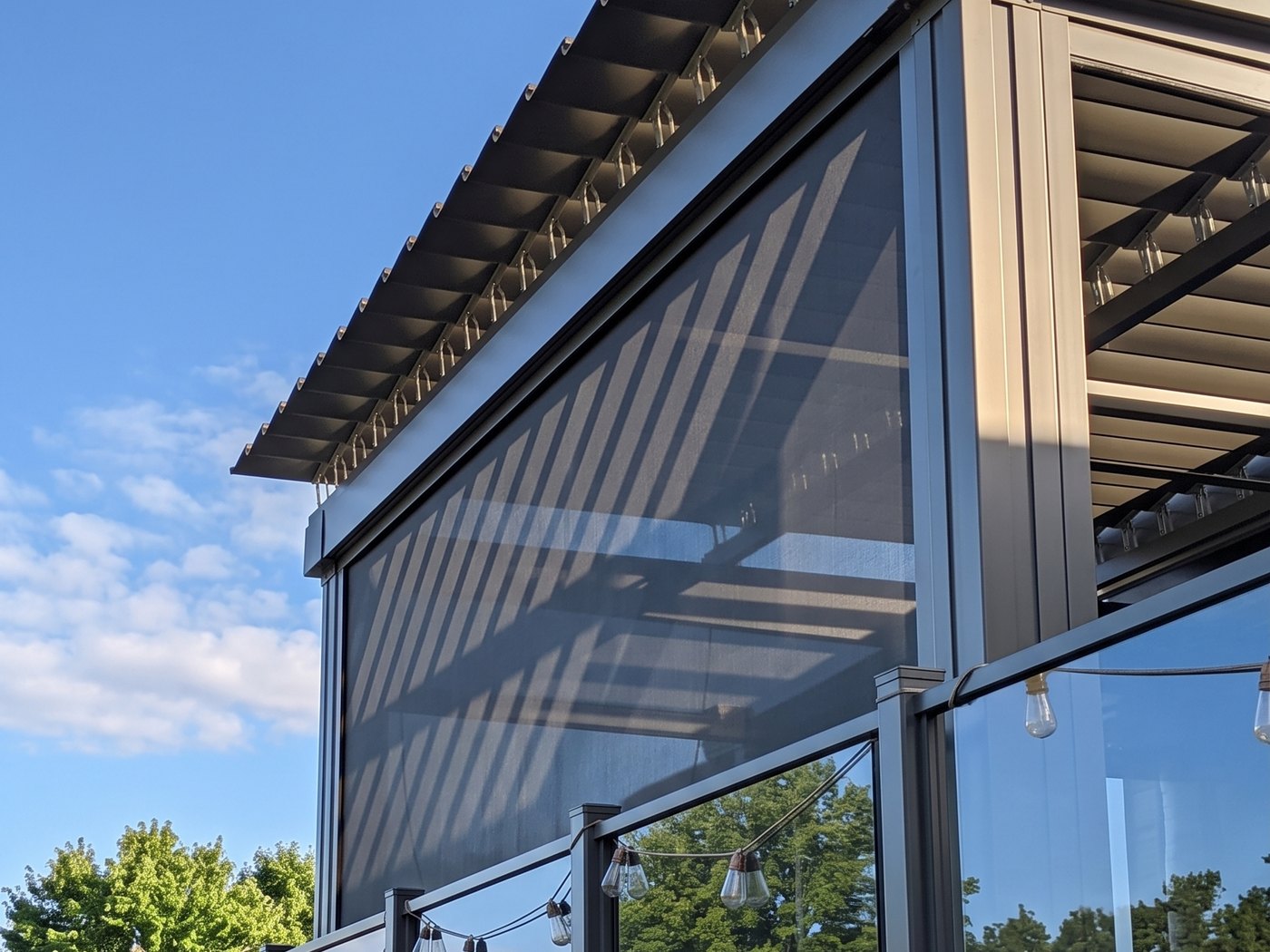 Cassette de toile motorisée encastrée sous la structure d'une pergola SunLouvre Pergolas foncée, profilés agencés à la couleur du cadre