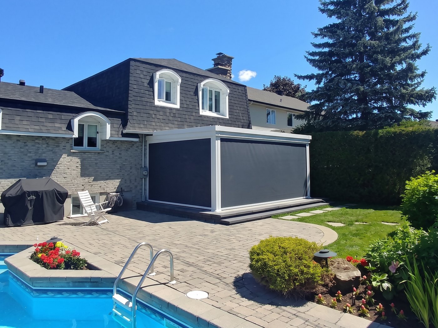 Pergola blanche SunLouvre Pergolas au bord d'une piscine, toiles motorisées foncées déployées sur deux côtés pour fermer l'espace