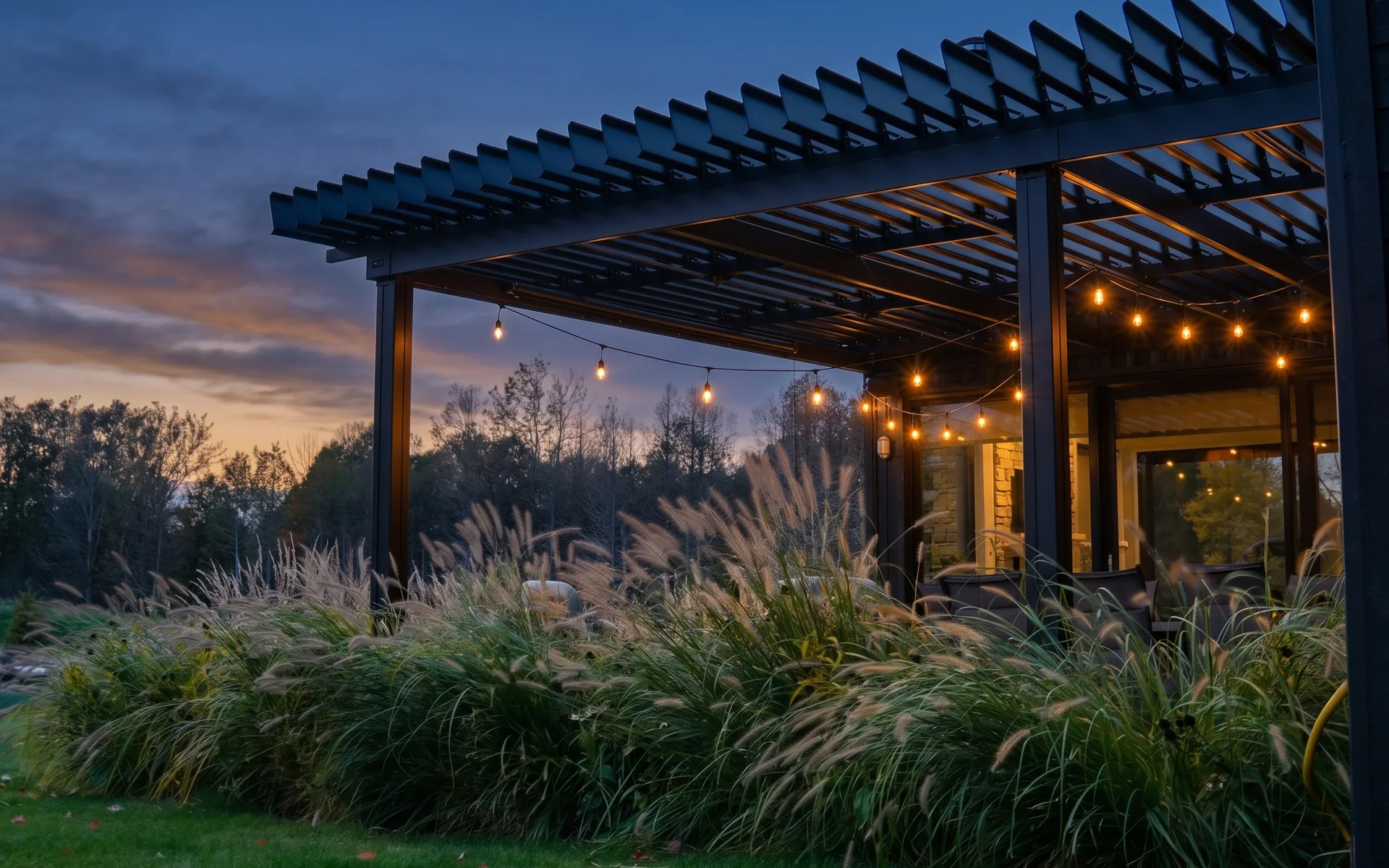 Pergola SunLouvre Pergolas sur une terrasse résidentielle, éclairée de guirlandes à la tombée du jour