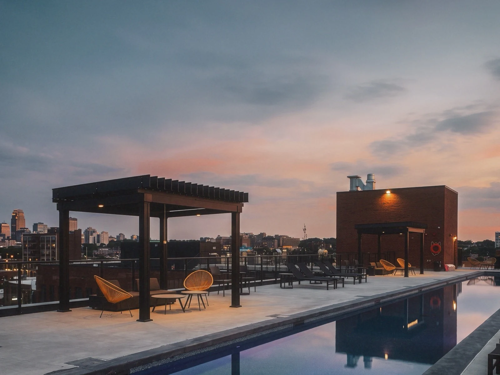 Pergola commerciale sur un toit-terrasse avec piscine, vue sur la ville au crépuscule