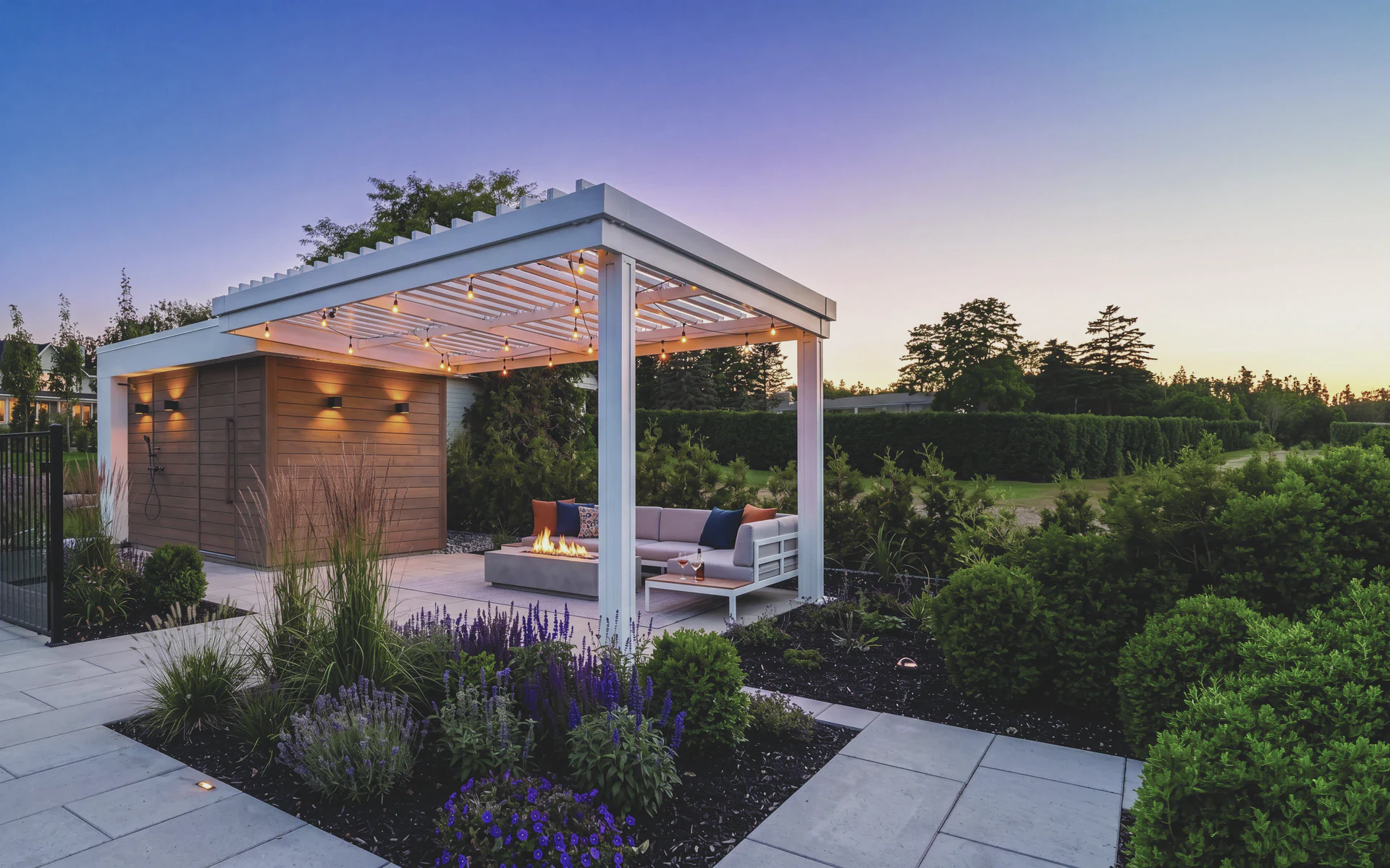 Pergola Lames intégrées blanche avec coin salon et foyer, sur une terrasse en soirée
