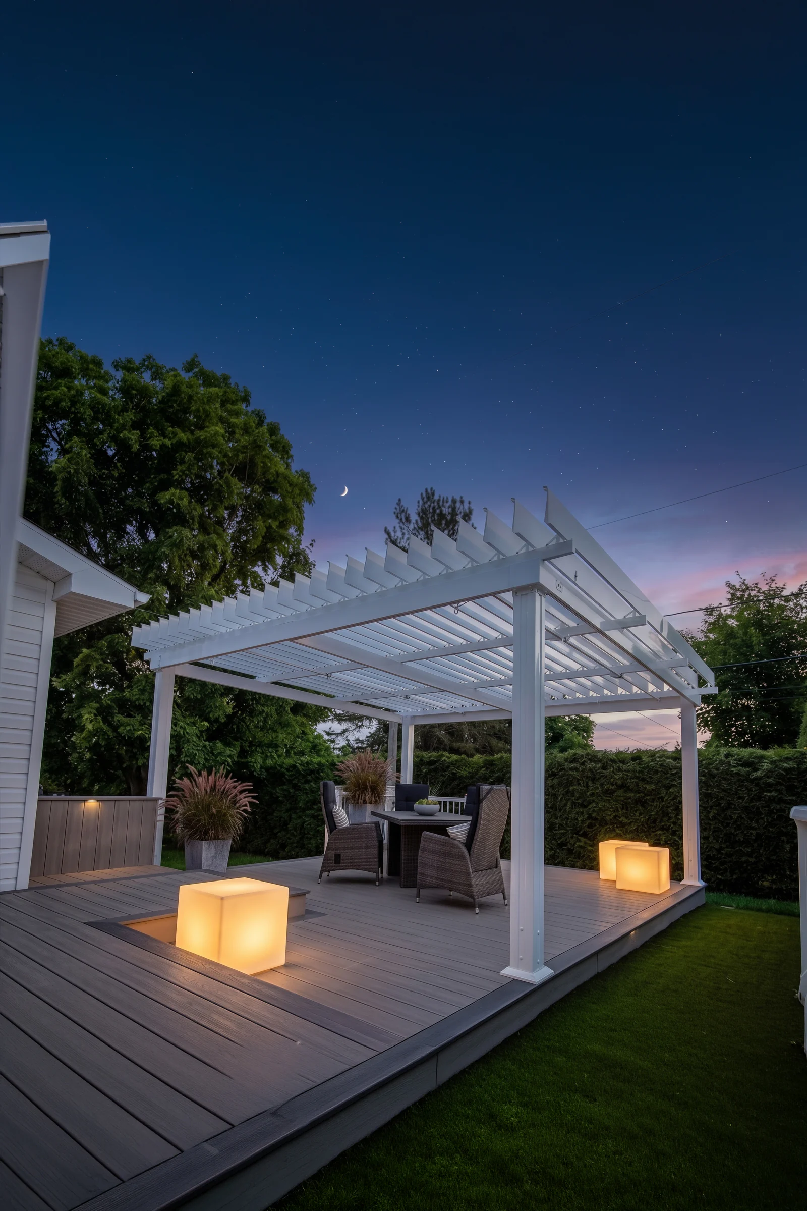 Pergola Classique blanche SunLouvre Pergolas au-dessus d'une terrasse avec table et fauteuils, cubes lumineux à la tombée de la nuit