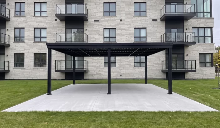 Black pergola on a concrete pad at the foot of the building, Aera Sacré-Coeur in Saint-Hyacinthe