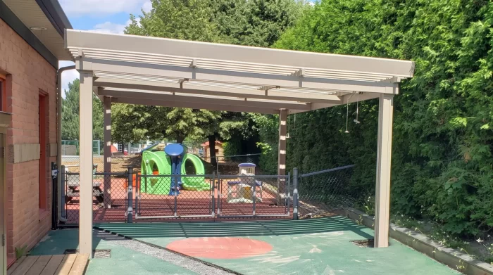 Pergola beige au-dessus de la cour de jeux de la garderie, CPE L'Apprenti-Sage à Mont-Saint-Bruno
