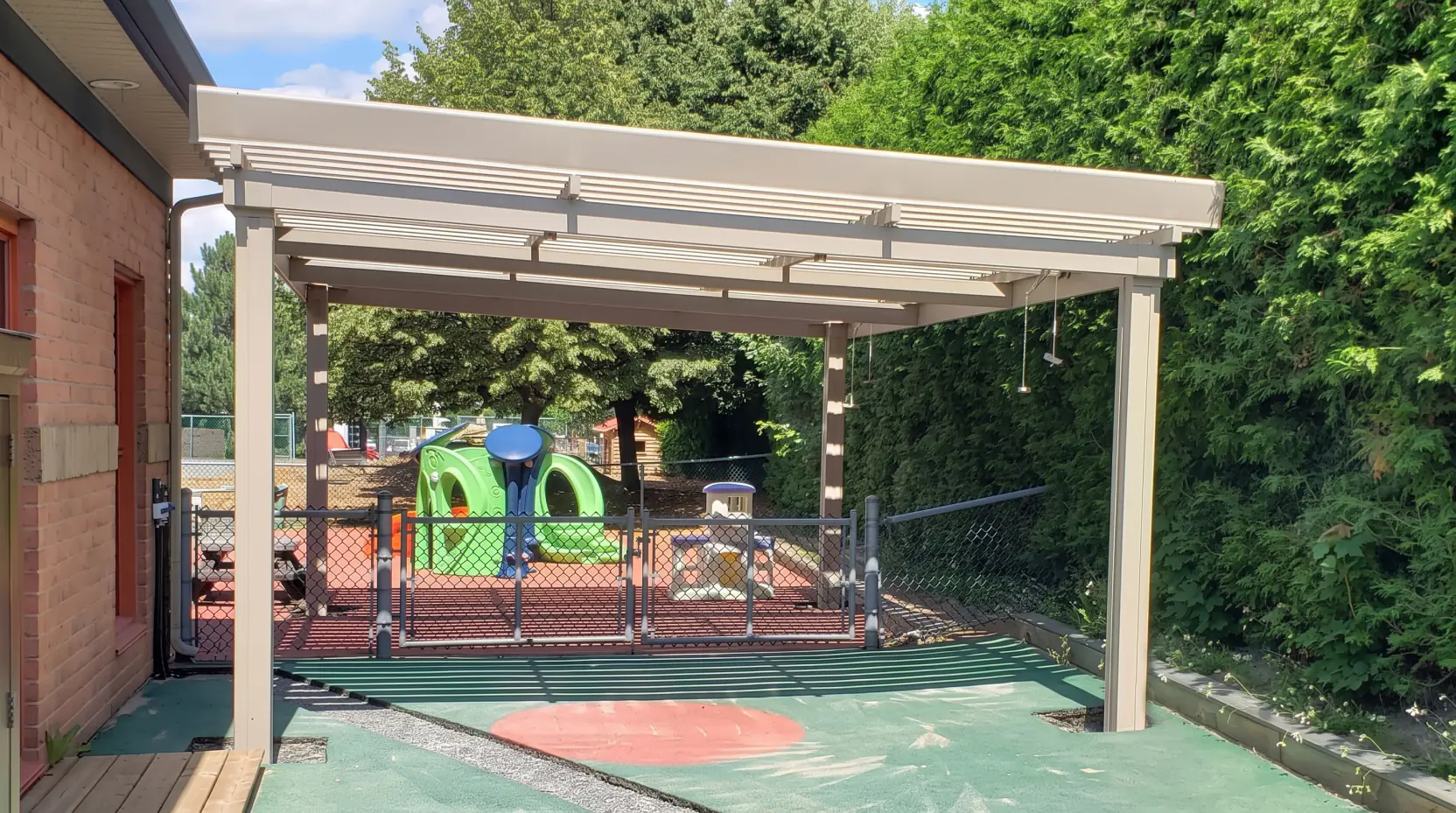 Pergola beige au-dessus de la cour de jeux de la garderie, CPE L'Apprenti-Sage à Mont-Saint-Bruno