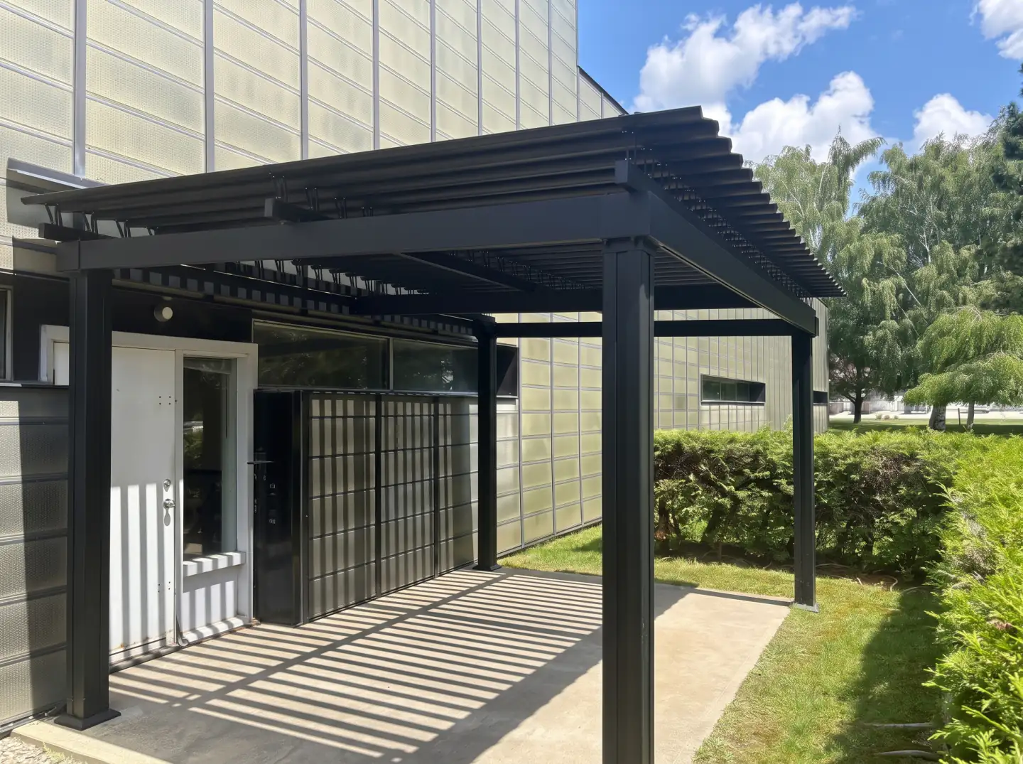 Passage couvert de lames sombres à l'entrée du bâtiment, Armtex à Magog