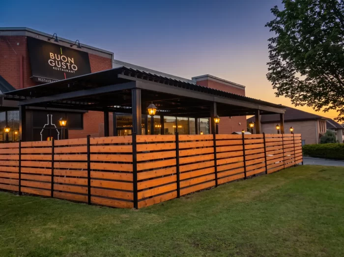 Terrasse abritée derrière une clôture de cèdre au crépuscule, Buon Gusto à Laval