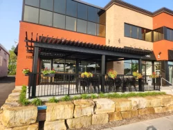 Terrasse longeant la façade de brique et de panneaux orangés, Cafellini à Saint-Bruno-de-Montarville