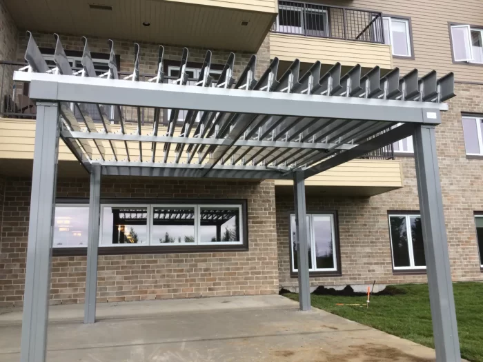 Grey pergola against the building over the patio, Château Bellevue in Baie-Comeau