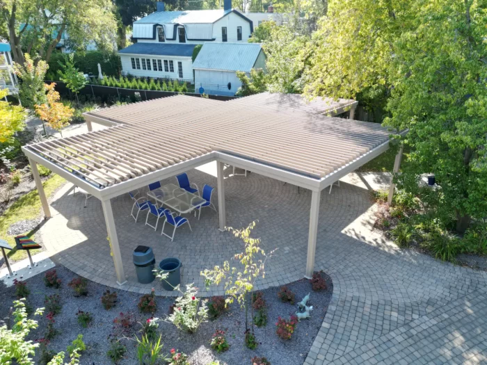 Paved courtyard and blue chairs under a beige pergola, CHSLD Jeanne-Crevier in Boucherville