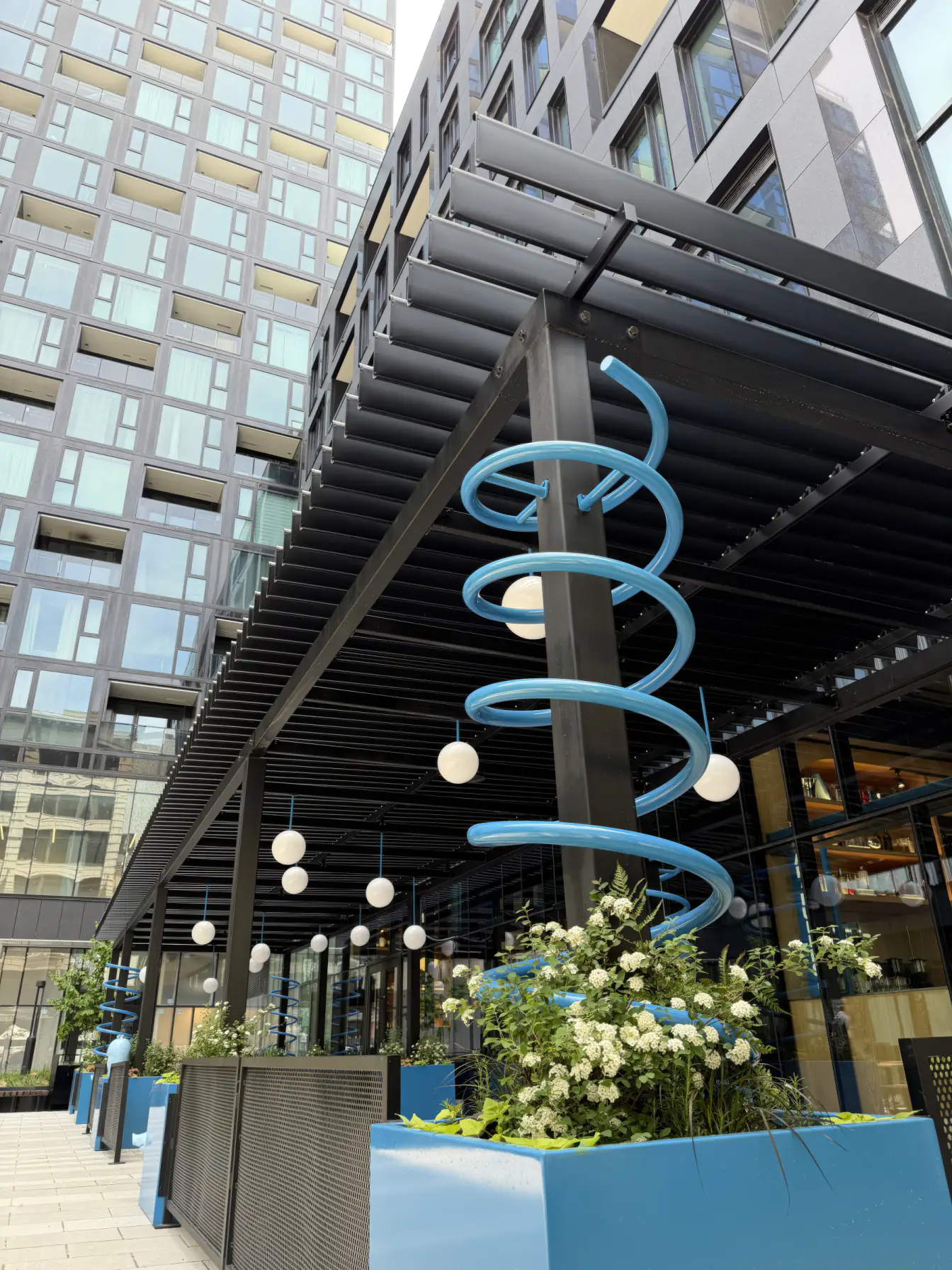 Terrasse sous la pergola noire au pied de la tour, Restaurant Cochon Dingue Maestria à Montréal