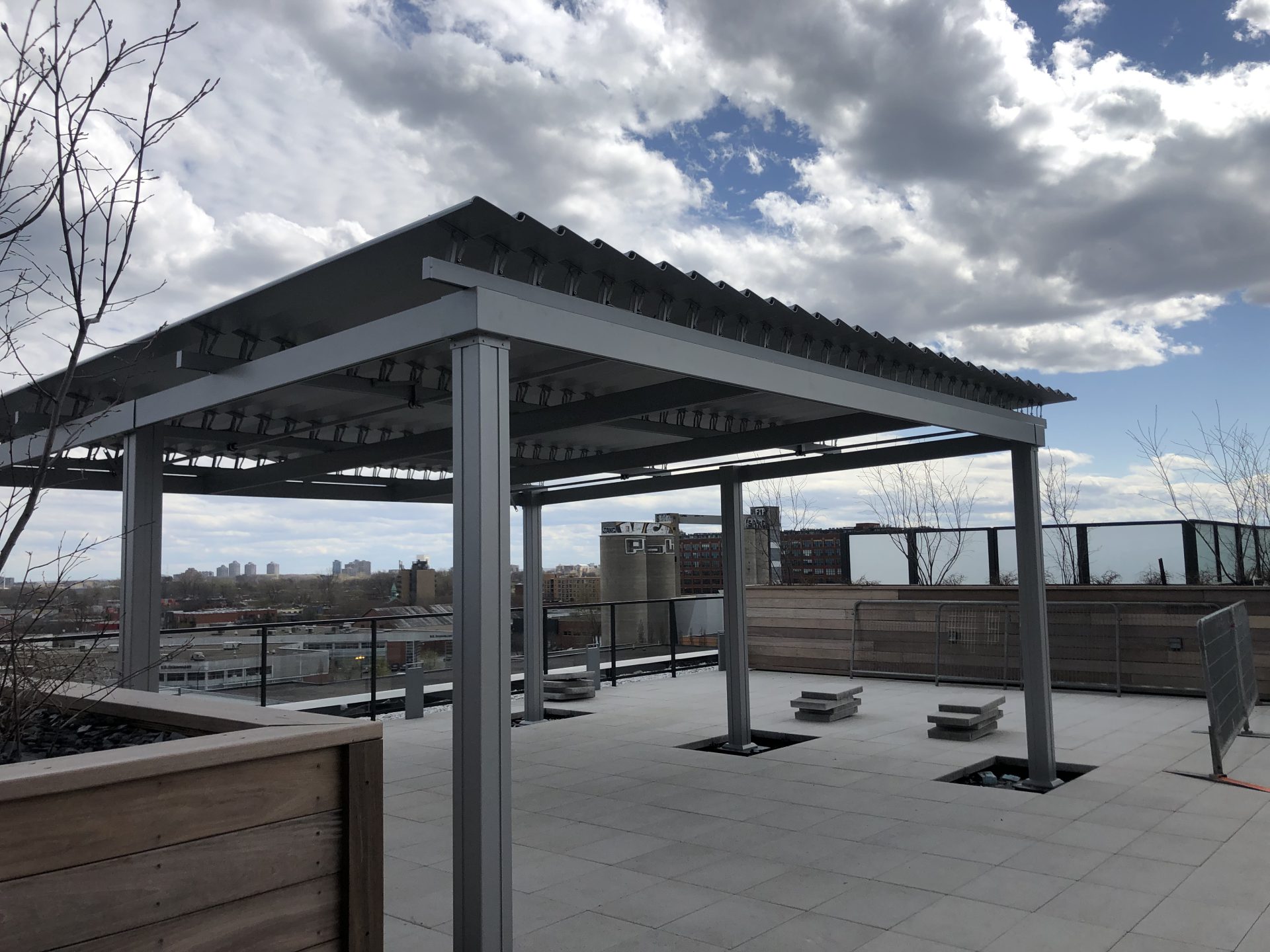 Grey pergola on the roof terrace with its wooden planters, Condos Bassins du Havre in Montréal