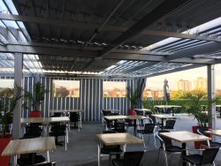 Tables sous les lames blanches et les rideaux rayés, Restaurant Cosmopolitain à Saint-Léonard