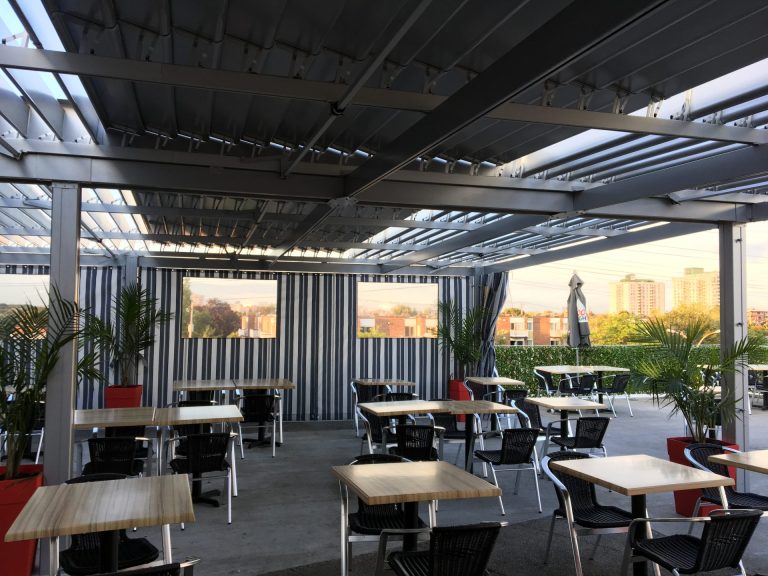 Tables sous les lames blanches et les rideaux rayés, Restaurant Cosmopolitain à Saint-Léonard
