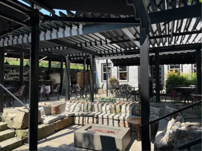 Pergola noire au-dessus de la terrasse de pierre et sa longue banquette, Domaine Jolivent à Lac-Brome