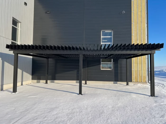 Black pergola against the metal building in winter, Enercycle in Saint-Étienne-des-Grès