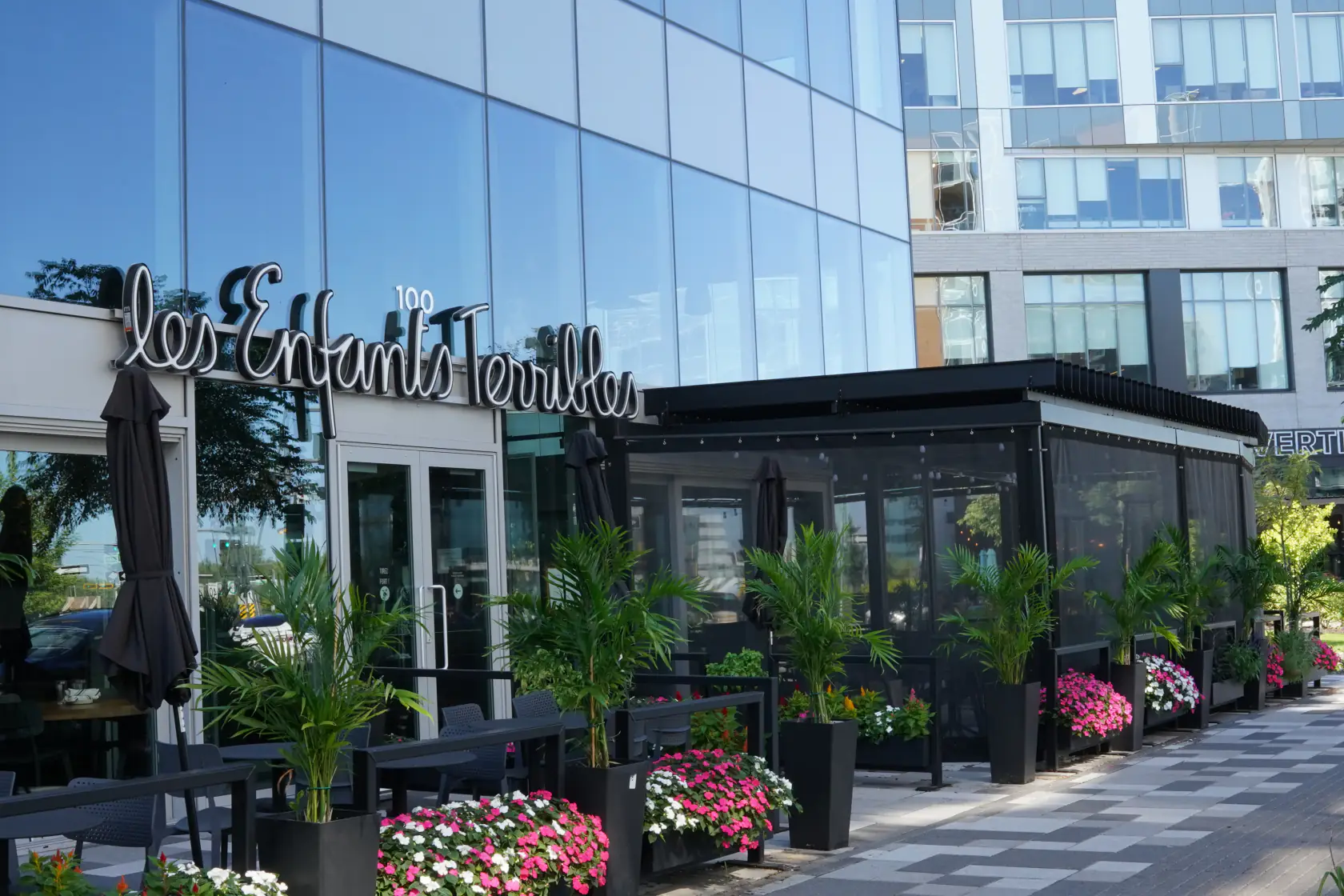 Terrasse vitrée et pergola noire devant le restaurant, Les Enfants Terribles à Brossard