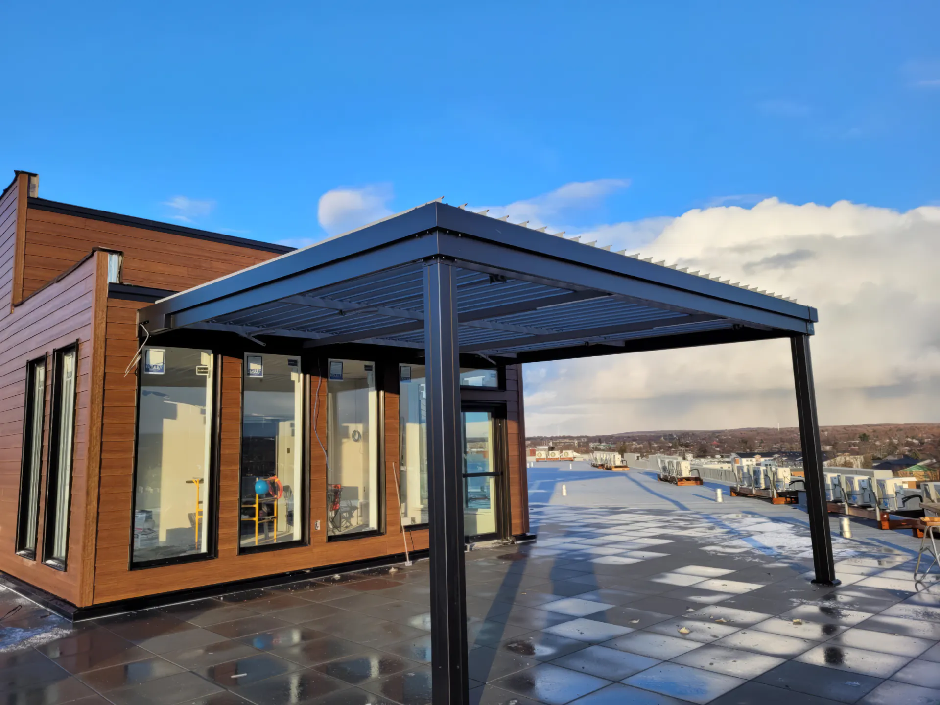 Black pergola on the roof terrace beside the wood-clad volume, Félicia in Granby
