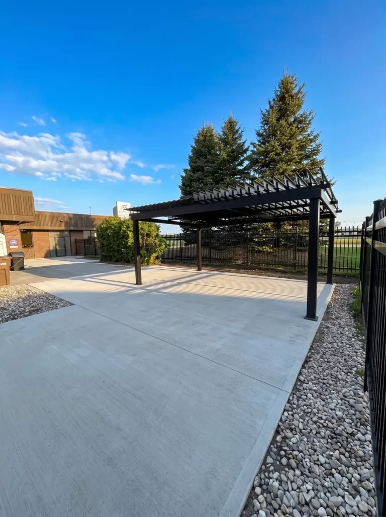 Black pergola on the concrete pad under a clear sky, Fempro in Drummondville