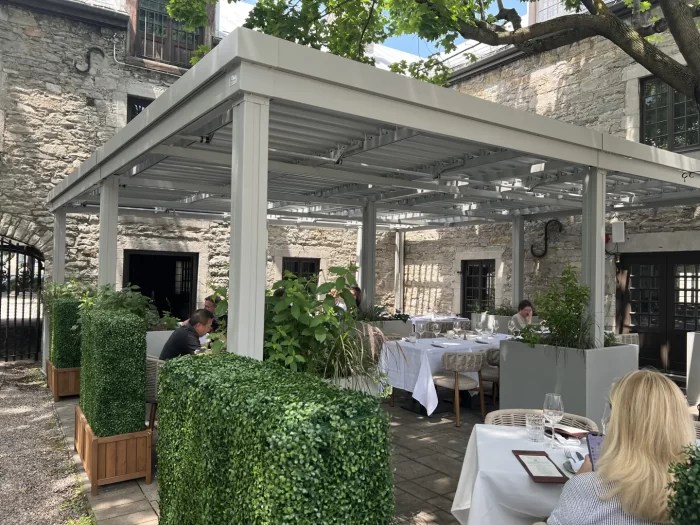 Pergola blanche au-dessus de la terrasse du restaurant dans la cour de pierre, Gibbys à Montréal