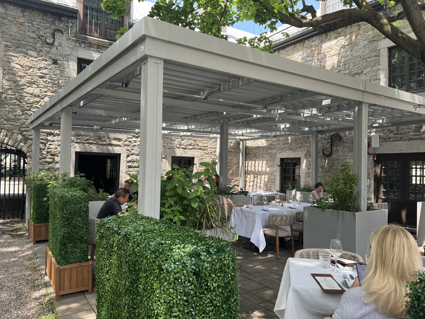 Pergola blanche au-dessus de la terrasse du restaurant dans la cour de pierre, Gibbys à Montréal