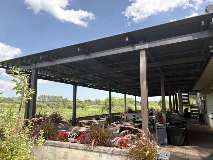 Terrasse de club de golf sous une pergola noire à lames, Golf de la Faune à Québec