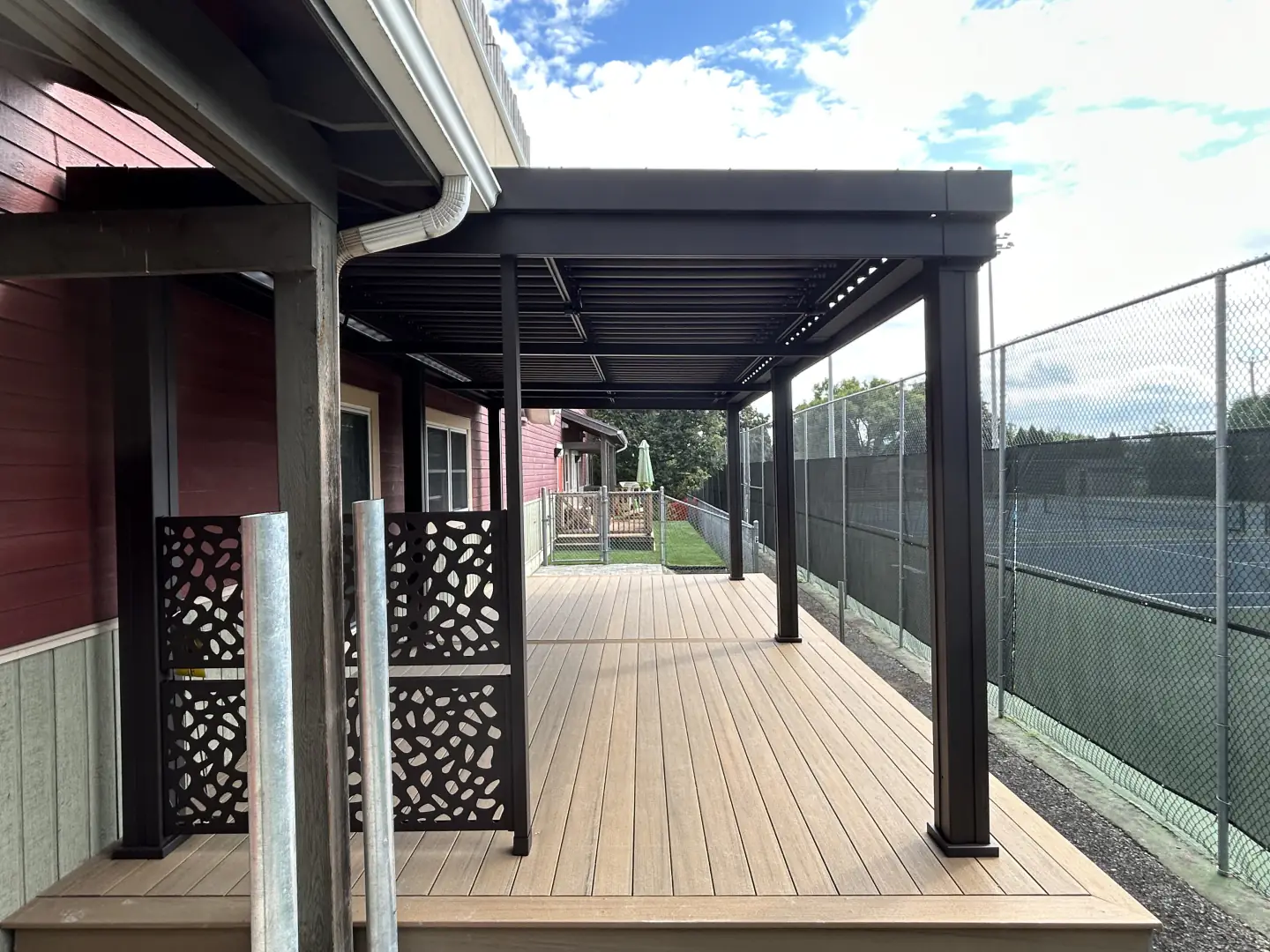 Black pergola over the wooden deck and its openwork screens, CPE Le Grand Chapiteau in Granby