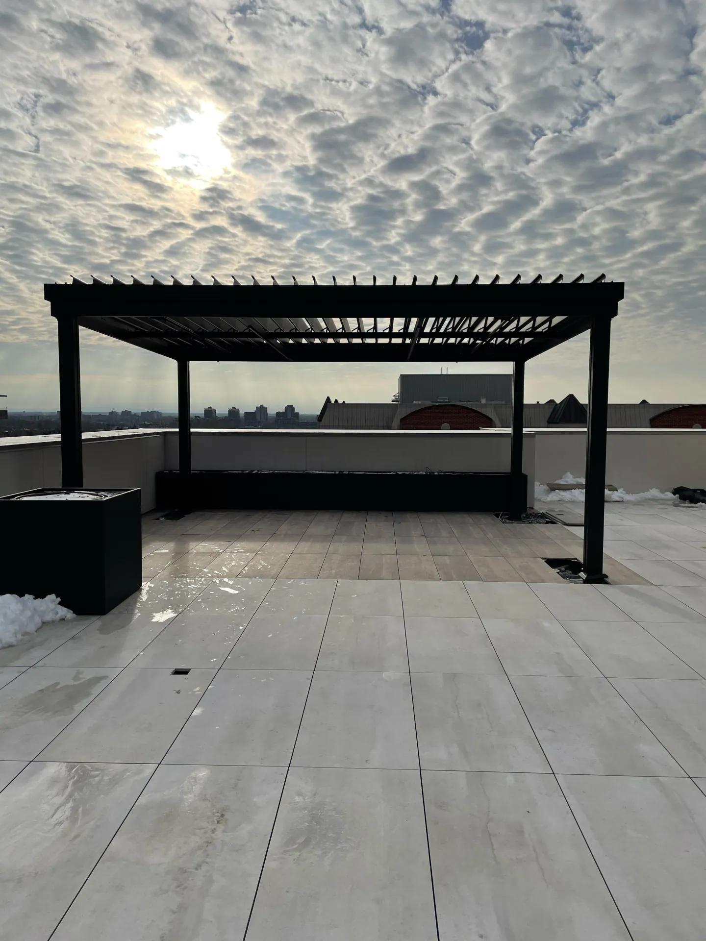 Pergola noire sur une terrasse de toit sous un ciel moutonné, Hampstead Majestic à Montréal