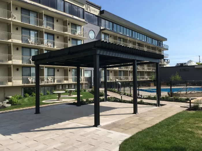 Black pergola over the paved courtyard near the pool, Hôtel Castel in Granby
