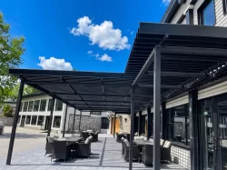 Pergola noire au-dessus de la cour et de son mobilier de rotin, Hôtel Mont Gabriel à Sainte-Adèle