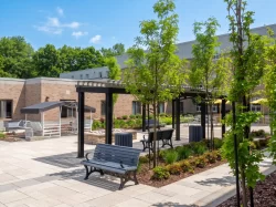 Bancs et jeunes arbres sous les pergolas noires de la cour, Centre d'hébergement Hubert-Maisonneuve à Rosemère