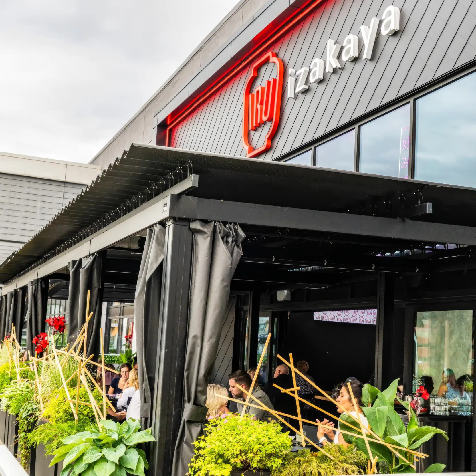 Black pergola and curtains over the terrace, beneath the sign, Iru Izakaya in Sainte-Foy