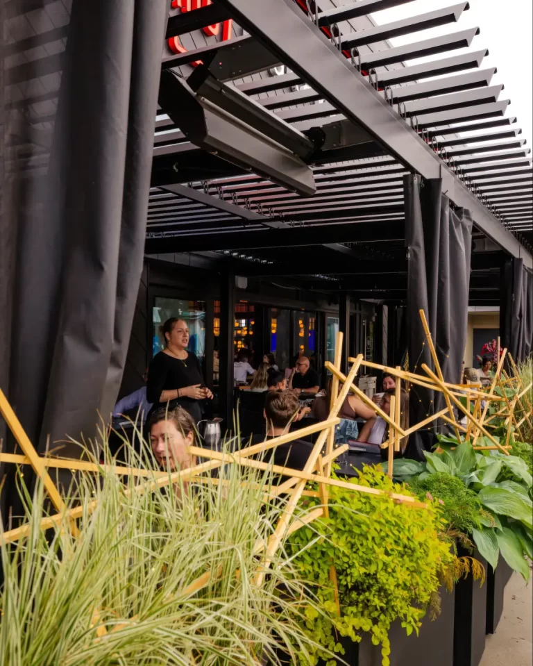 Guests on the terrace under the louvers, grasses in the foreground, Iru Izakaya in Sainte-Foy
