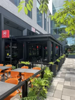 Terrasse aux chaises orange sous la pergola noire, Iru Izakaya à Brossard