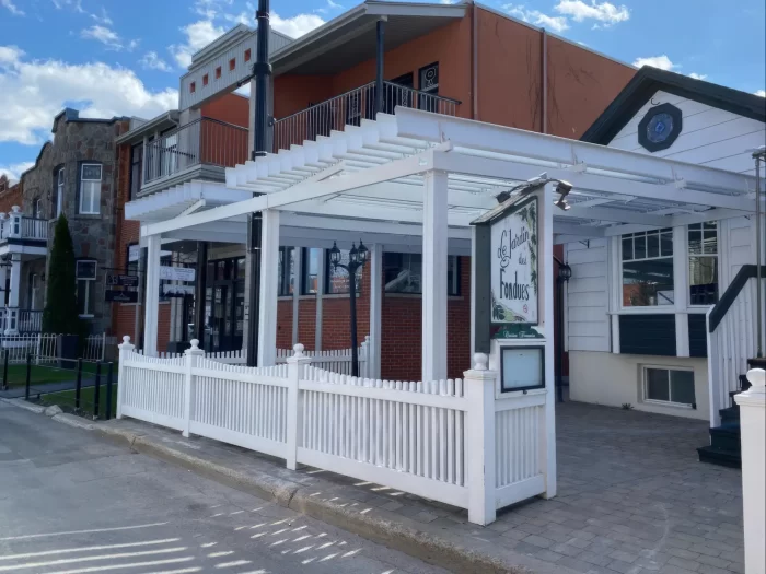 Pergola blanche au-dessus de la terrasse close d'une clôture à piquets, Le Jardin des Fondues à Terrebonne