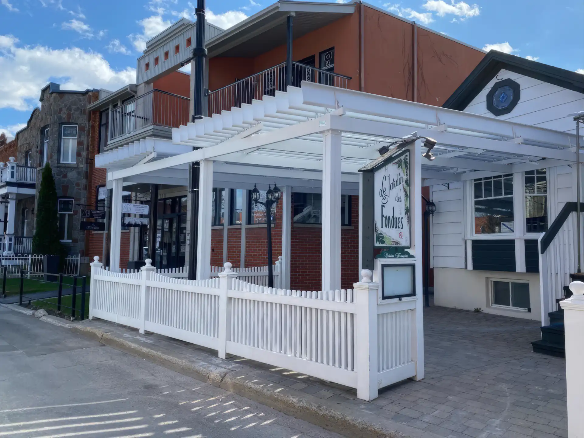 Pergola blanche au-dessus de la terrasse close d'une clôture à piquets, Le Jardin des Fondues à Terrebonne
