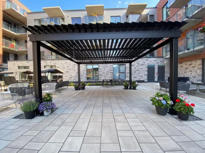 Pergola noire au-dessus de la cour pavée entre les immeubles, Jazz Condos à Saint-Bruno-de-Montarville