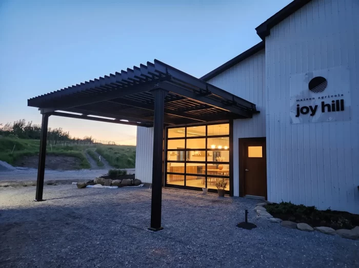 Pergola noire à l'entrée du bâtiment éclairé au crépuscule, Maison agricole Joy Hill à Frelighsburg
