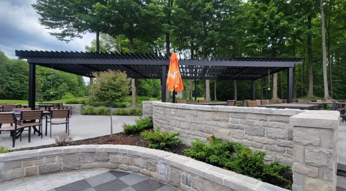 Black pergola over the terrace with its stone walls, Club de golf Le Blainvillier in Blainville