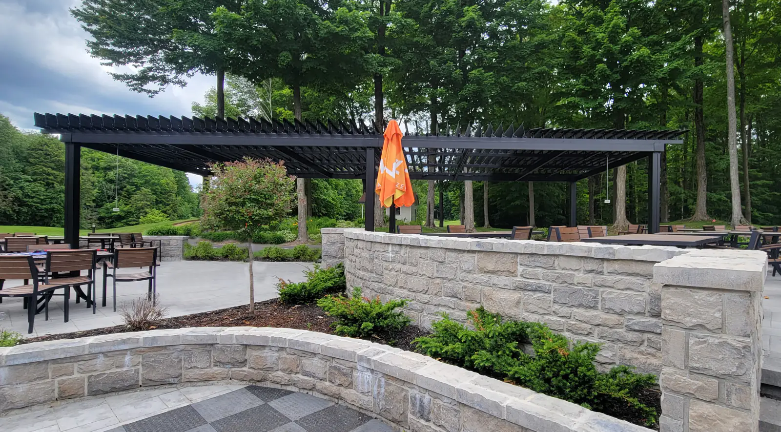 Black pergola over the terrace with its stone walls, Club de golf Le Blainvillier in Blainville