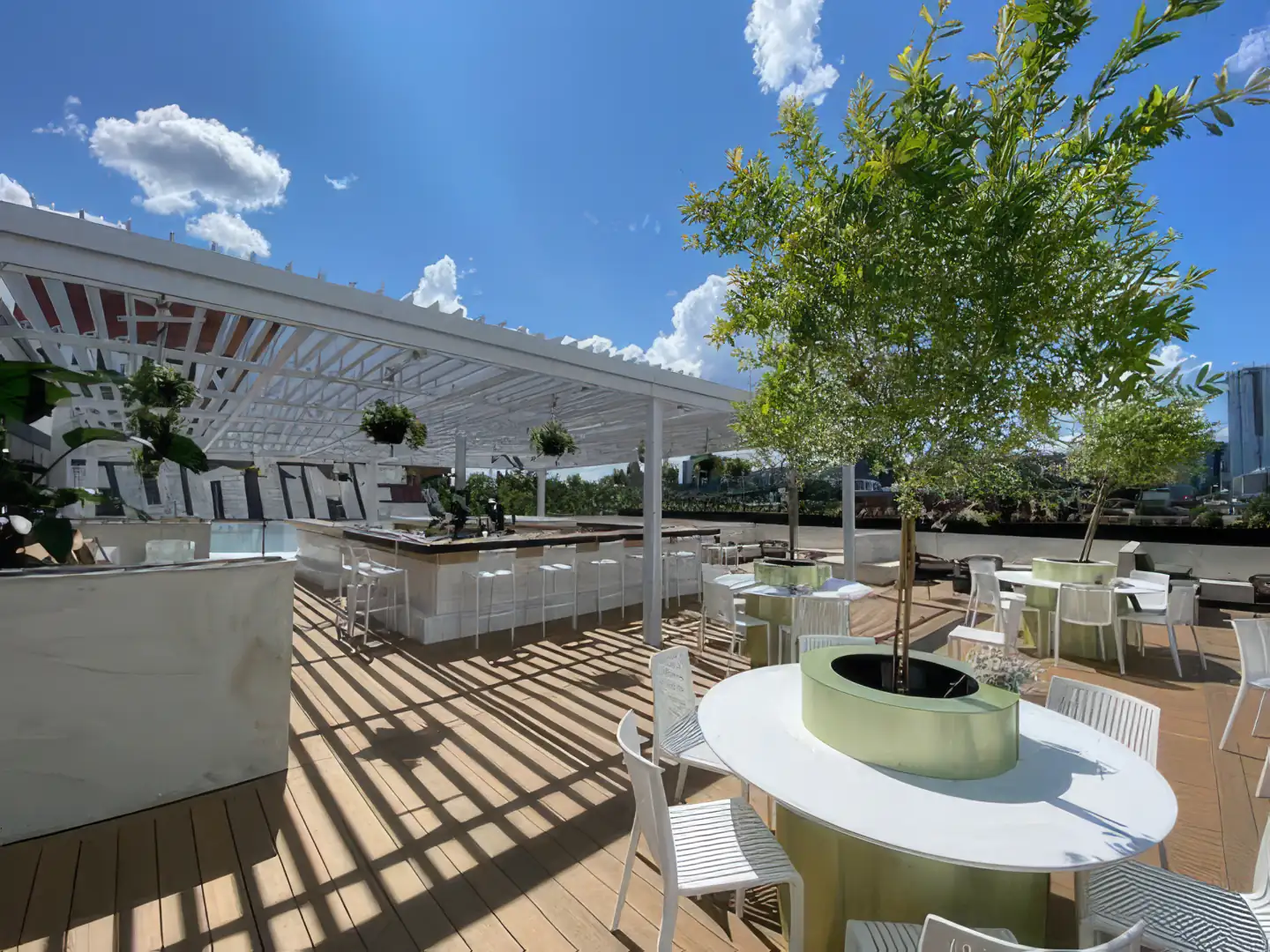Terrasse de toit avec bar et tables sous une pergola blanche, Le Parloir à Montréal