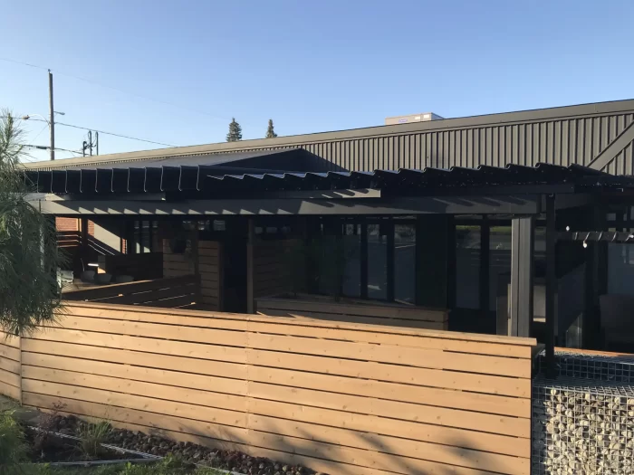 Pergola noire au-dessus de la terrasse close d'une clôture de bois, Le Robusto à Granby