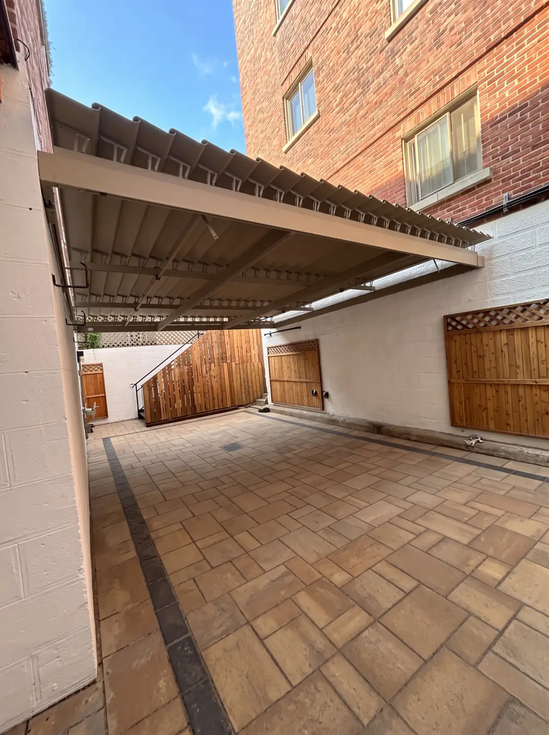 Beige canopy over the paved passage alongside the brick building, Résidence Lev-Tov in Montréal
