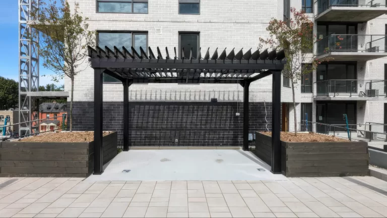 Cour pavée et bacs de plantation sous la pergola noire, Résidence LIZ à Montréal