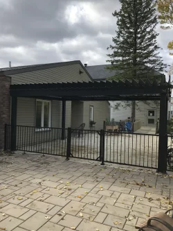 Pergola adossée au bâtiment derrière la clôture, Manoir Soleil à Chambly